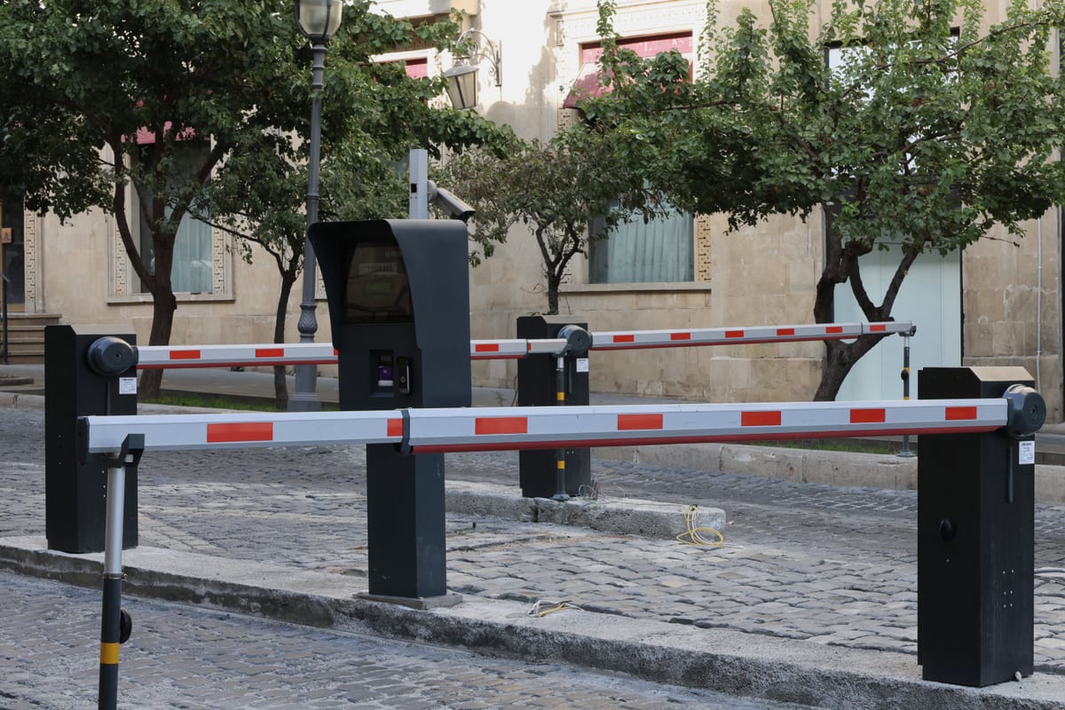 A modern automated parking barrier at a car park entrance lane, one of the components that moves the cost of an ANPR system.