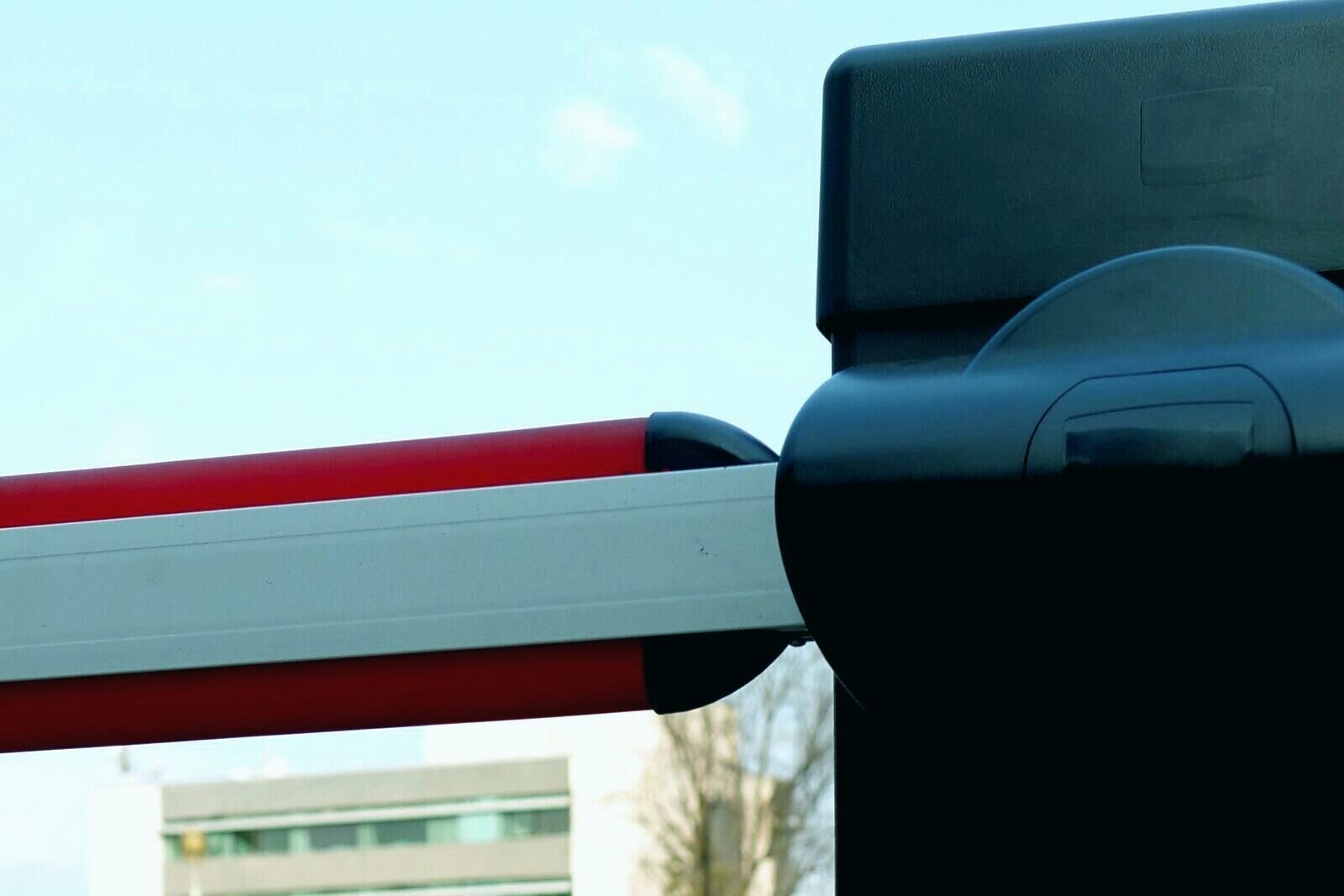 Car park entry barrier arm raised at an access control column, the physical stop that keeps unauthorised vehicles off private land