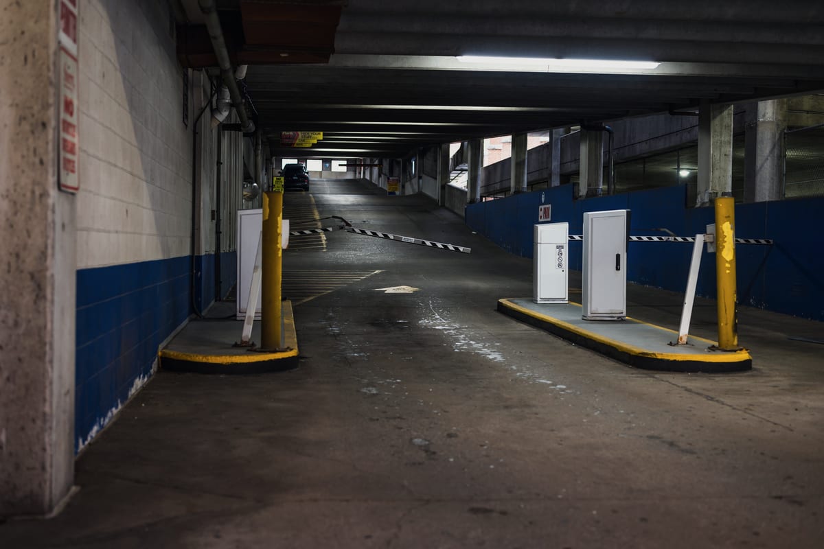 Car park entrance and exit lane with raised barrier arms and access columns, where a camera reads the plate on arrival